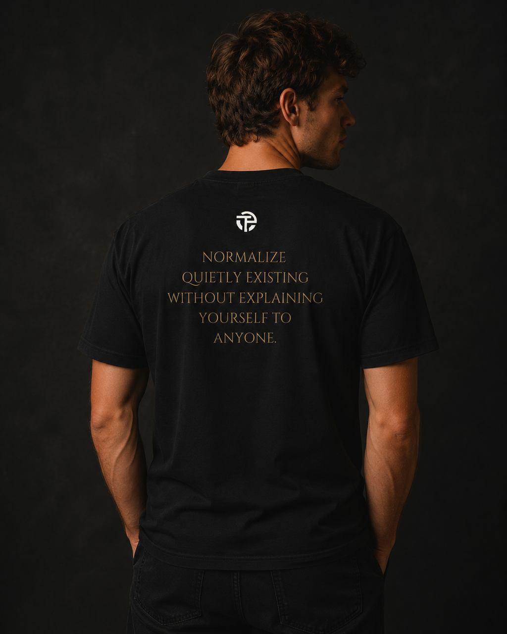Model wearing the TPC Quietly Existing Variant A black tee, back view with the quote